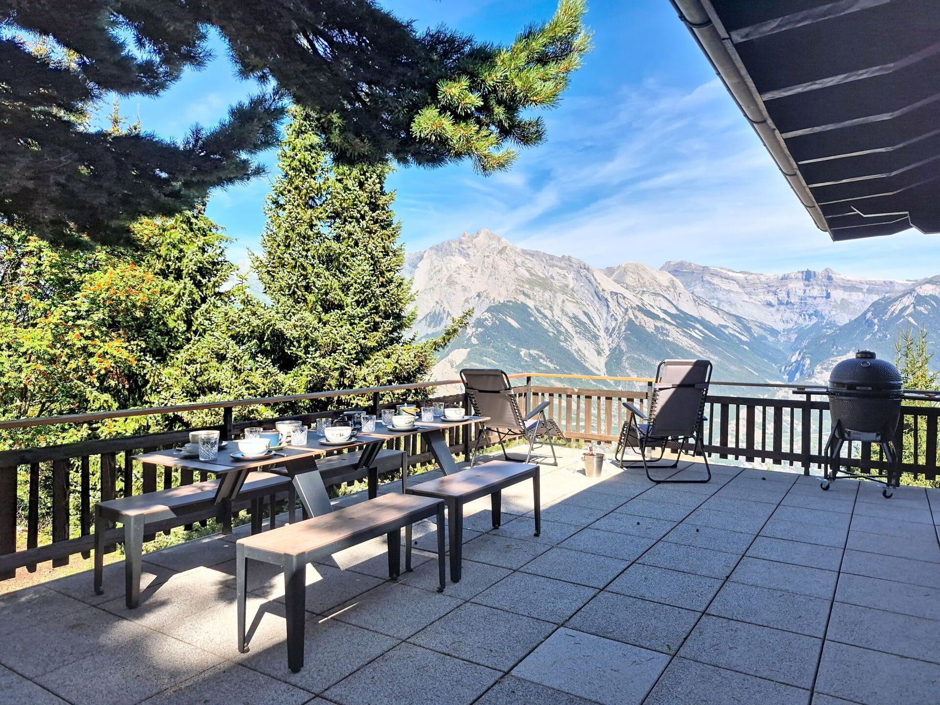An outdoor patio with tables and chairs, overlooking a mountainous landscape.