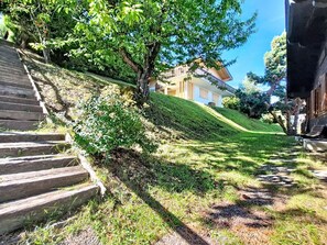 Ein Wohnhaus mit einer Treppe, die einen grasbewachsenen Hang hinaufführt, ein Haus mit einem Balkon und einem strahlend blauen Himmel.