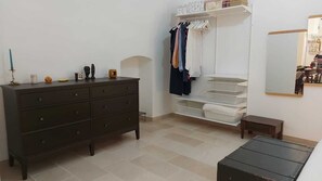 A bedroom with a dark wooden dresser, a white closet with hanging clothes, a small bedside table, and a mirror on the wall. - Marilu, a Cozy and Central Vacation Rental Apartment in the City Center. (Trani)