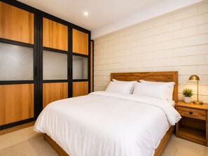 A bedroom with a bed, nightstand, lamp, and a wardrobe with frosted glass panels. - Mwalosun Luxury Vintage Apartments (Kampala)
