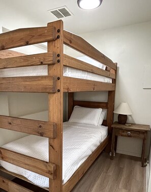 Una cama literaria con barandillas de madera y una mesita de noche con lámpara.