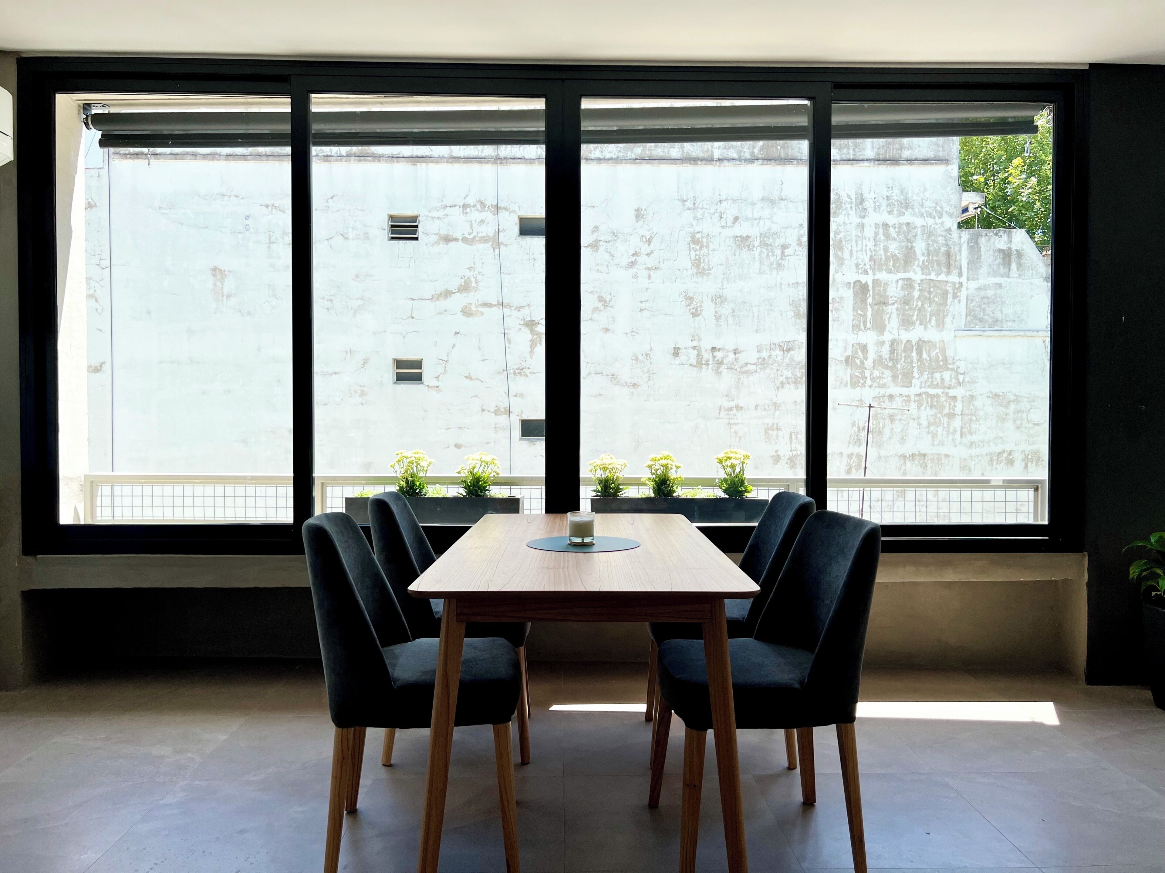 Una habitación moderna con un ventanal grande, una mesa de madera y cuatro sillas.