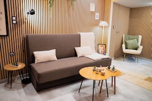Ein modernes Wohnzimmer mit einer braunen Couch, zwei Beistelltischen und einem Sessel.