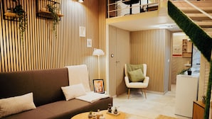 A modern living room with a brown sofa, a white chair, a small round table, and a striped wall.