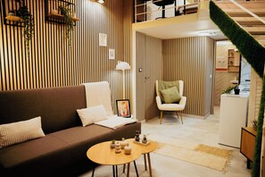 Un salon moderne avec un canapé marron, un fauteuil blanc, une petite table ronde et un mur à rayures.