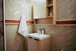 Une salle de bain avec un mur en marbre, un meuble-lavabo en bois, un évier, une serviette et un miroir.