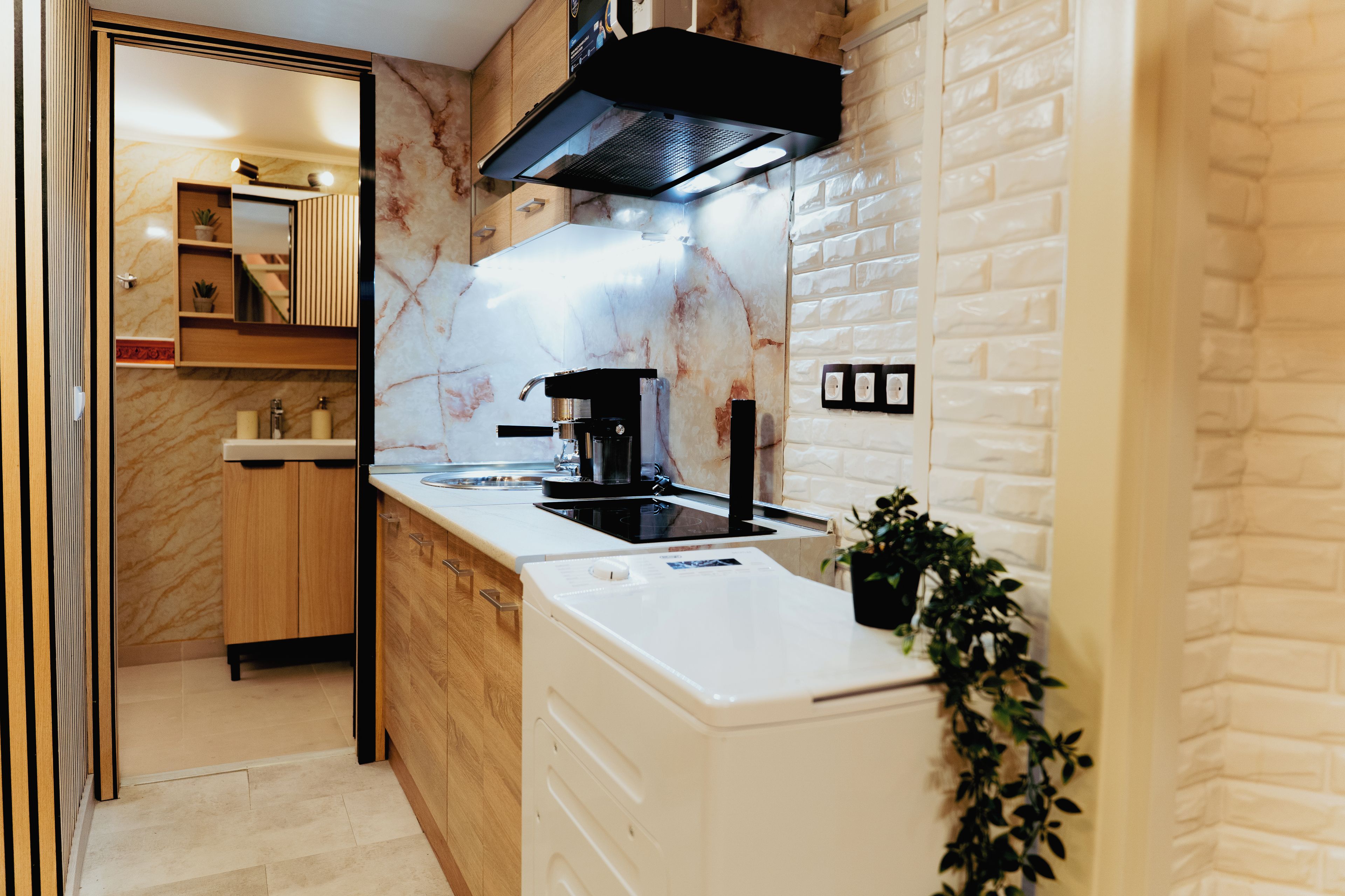 A modern kitchen with a marble backsplash, a black range hood, and a white countertop.
