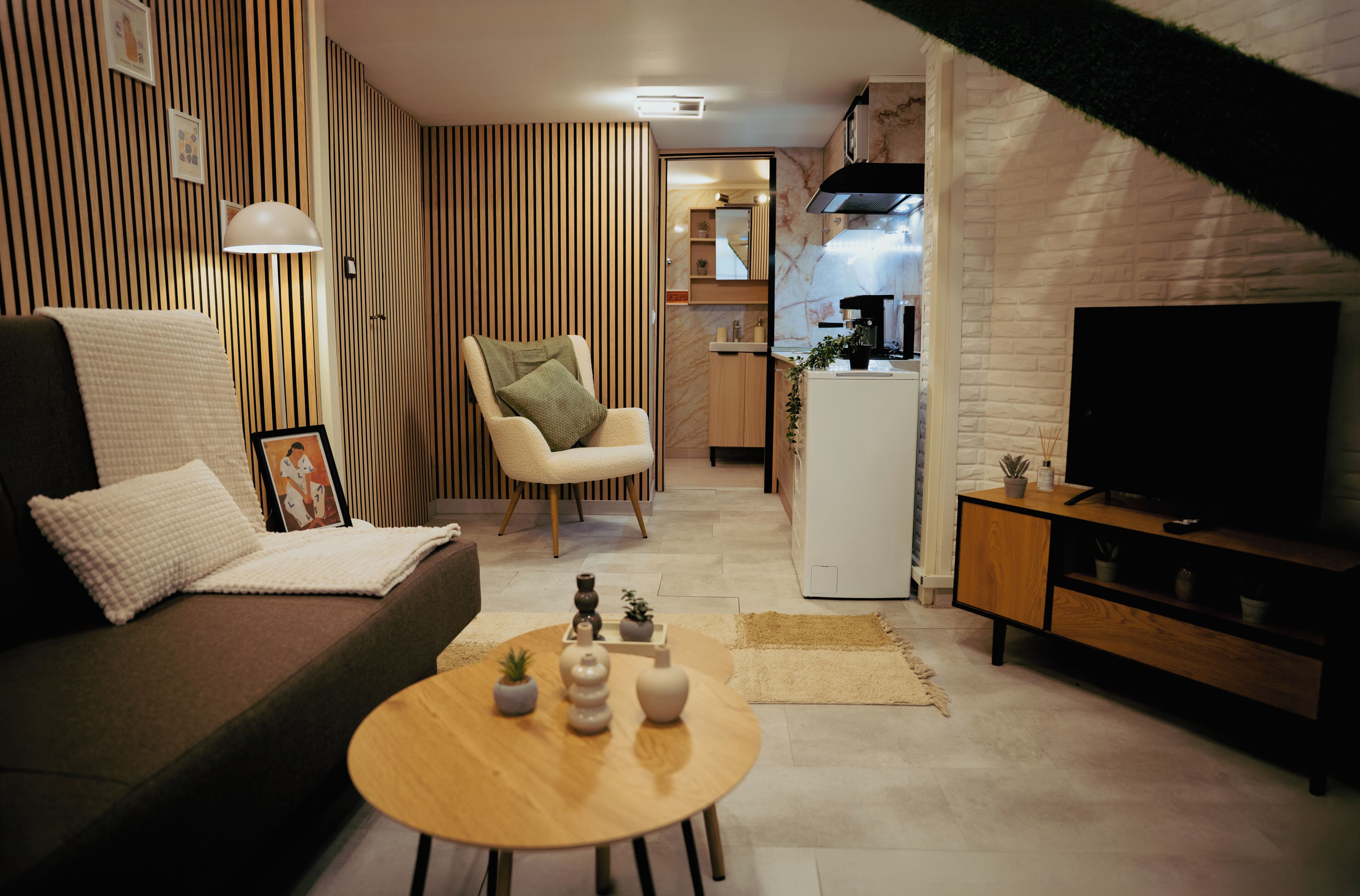 A modern living room with a sofa, armchair, coffee table, and a television.