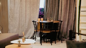 A cozy room with a round table, two chairs, a small potted plant, and a window with curtains.