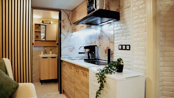 A compact kitchen with a built-in stove, a coffee machine, and a microwave.
