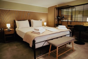 Ein Hotelzimmer mit Bett, Nachttischen, einer Bank, einem Schreibtisch und einem Spiegel.
