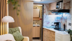 A compact kitchen with a built-in microwave, a coffee machine, and a sink.