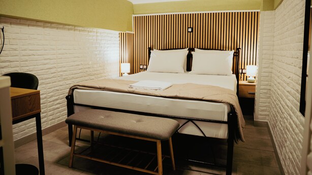 A neatly arranged hotel room with a bed, bedside tables, a bench, and a desk.