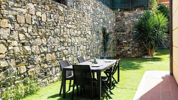 Un muro in pietra con un tavolo e sedie per mangiare all'aperto.