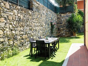 Un mur de pierre avec une table et des chaises disposées pour prendre les repas en plein air.