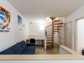 Un salon moderne avec un canapé bleu, un bureau et un escalier en colimaçon.