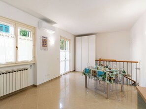 Une pièce spacieuse avec une table à manger dressée pour quatre personnes, un radiateur et un escalier doté d’une rampe en bois.