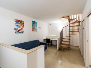Ein modernes Interieur mit einer Treppe, einem Sofa, einem Schreibtisch und zwei Bildern an der Wand.