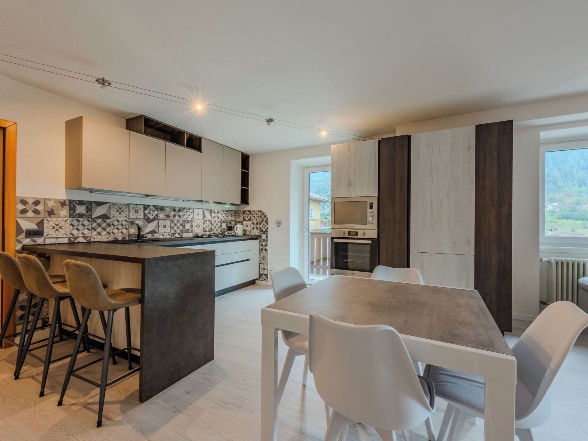 Cocina moderna con una isla central, taburetes de bar y un comedor con mesa y sillas.