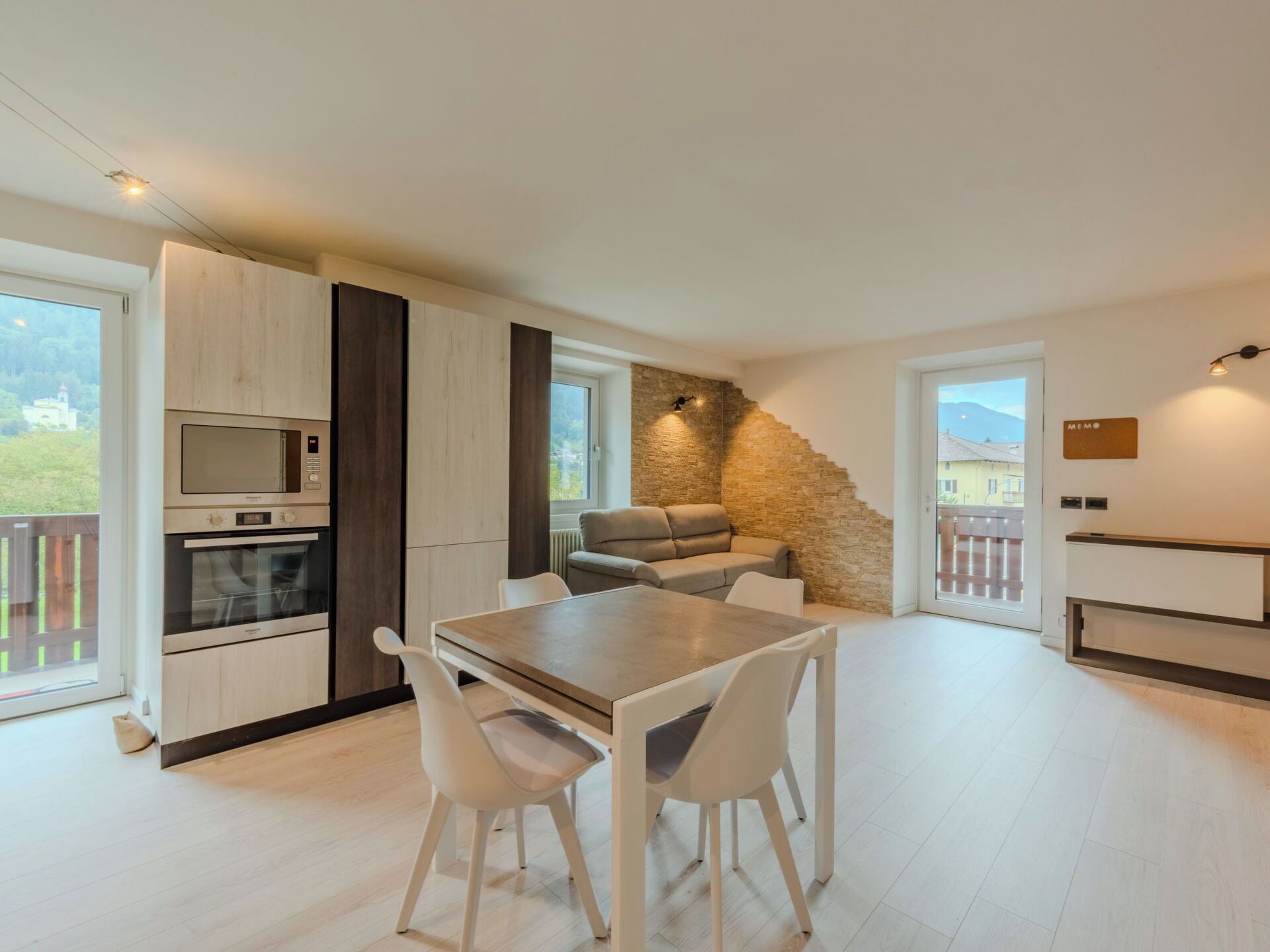 A modern kitchen with built-in appliances, a dining area with a table and chairs, and a stone accent wall.