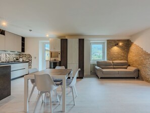 Eine moderne Küche mit Essbereich, einer Couch und einer Wand mit Steindekor.