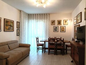 Ein Wohnzimmer mit einer Couch, einem Esstisch, Stühlen und Kunstwerken an den Wänden.