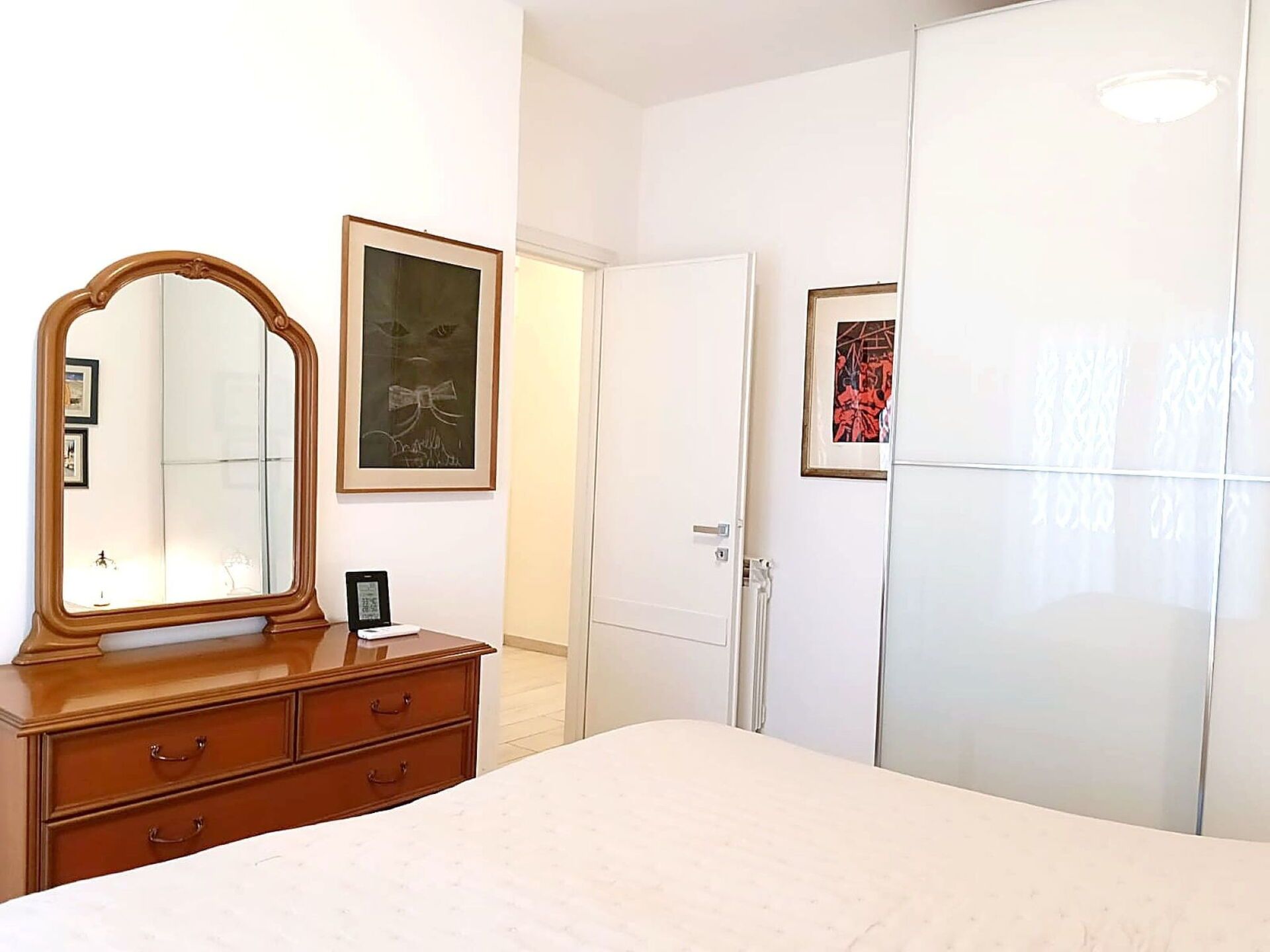 Un dormitorio con una cama grande, un aparador de madera, un espejo y dos puertas.