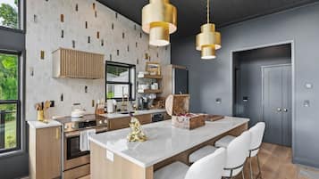 Una cucina moderna con isola centrale, sgabelli da bar e illuminazione a sospensione.