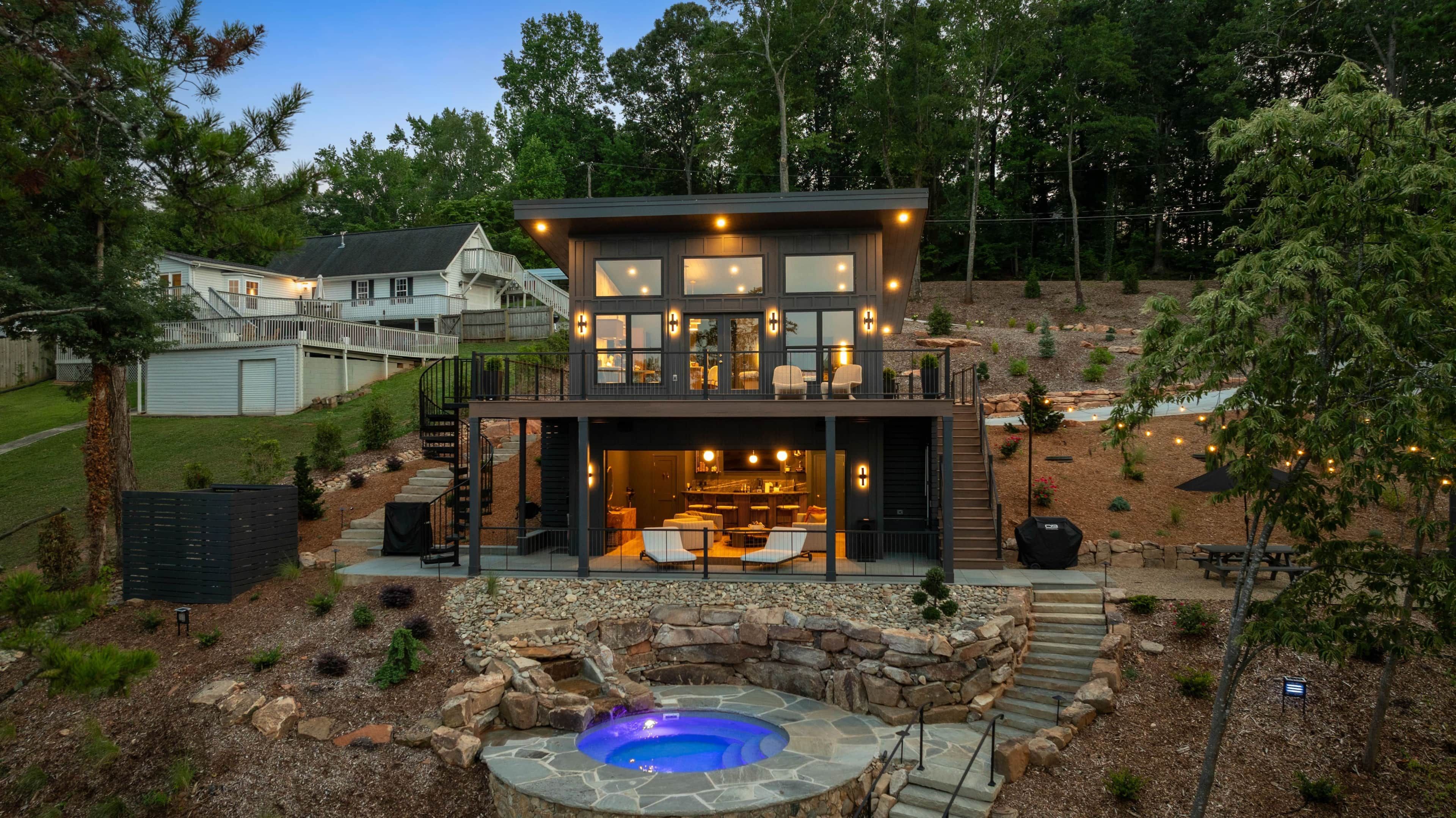 A two-story house with a visible outdoor kitchen area and a hot tub.