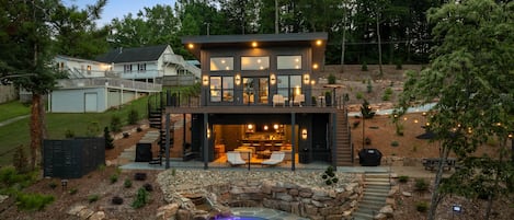 A two-story house with a visible outdoor kitchen area and a hot tub.