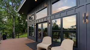 A modern exterior with large windows and a wooden deck. - The Black Pearl - Lake Bowen - Luxury Waterfront (Inman)