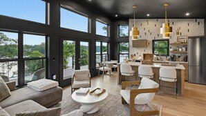 A modern interior with a dining area, kitchen, and seating space with large windows. - The Black Pearl - Lake Bowen - Luxury Waterfront (Inman)