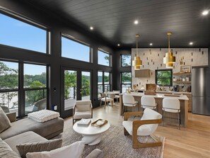 Ein modernes Interieur mit Essbereich, Küche und Sitzgelegenheiten, versehen mit großen Fenstern.