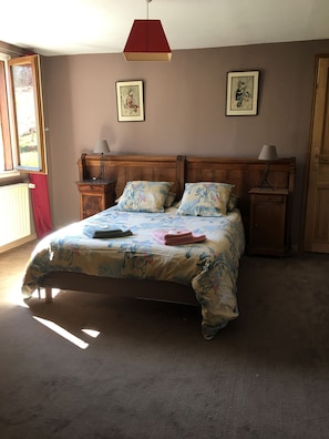 Un dormitorio con una cama, dos mesitas de noche, un ventanal y dos cuadros colgados en la pared.