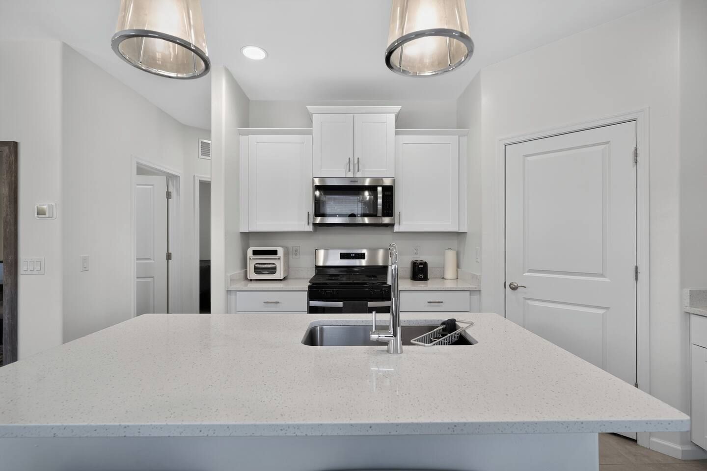 A modern kitchen with white cabinetry, stainless steel appliances, and a central island with a sink.