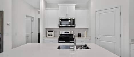 Una cocina moderna con armarios blancos, electrodomésticos de acero inoxidable y una isla central con un lavamanos.