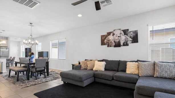 A modern living room with a sectional sofa, a dining area with a chandelier, and a kitchen in the background. - Mins to Banner* St. Mary’s* El Rio* TUS Airport (Tucson)