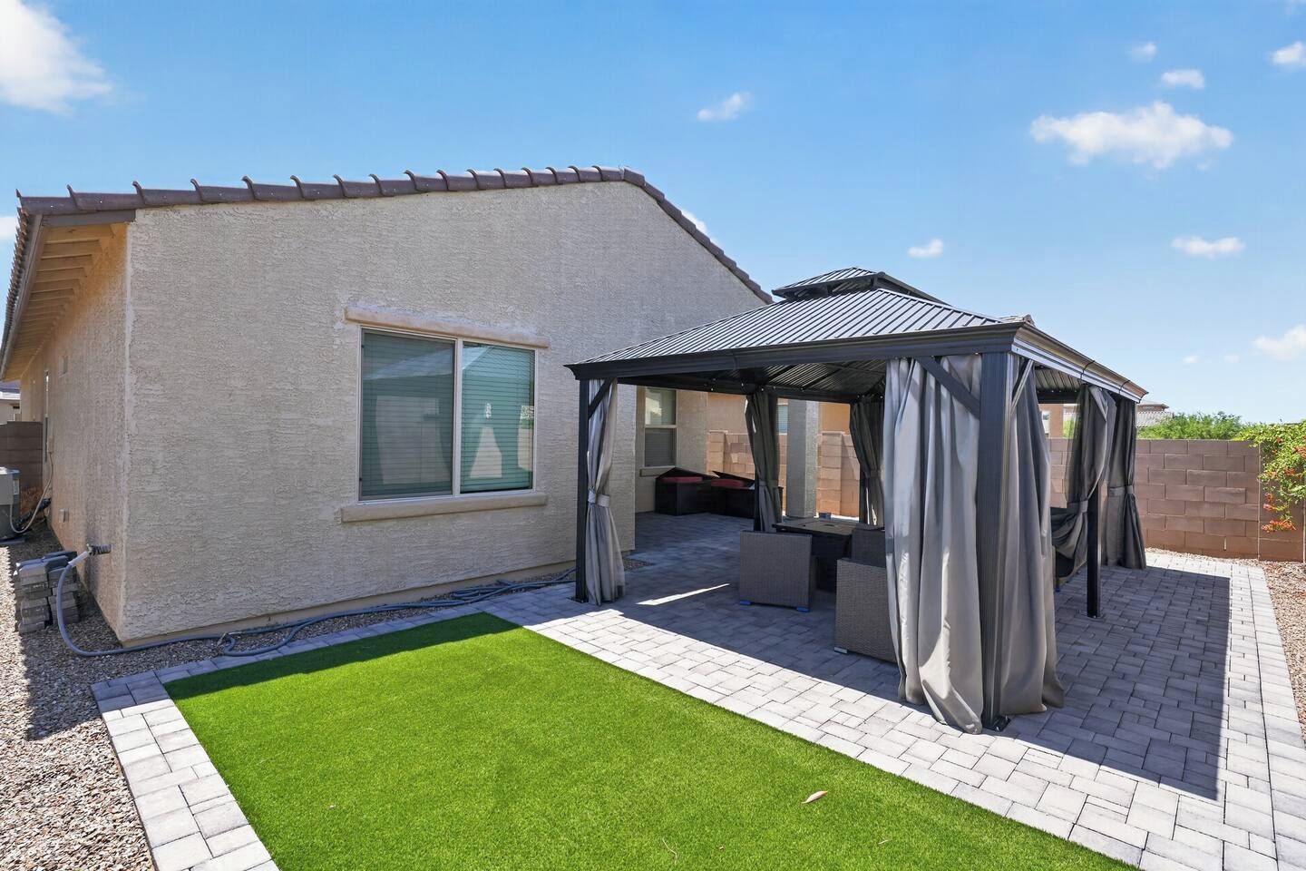 Une maison dotée d’un patio, d’un espace extérieur aménagé et couvert, et d’une pelouse bien entretenue.