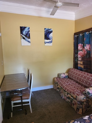 Ein Zimmer mit einem Esstisch, einer Couch und zwei an der Wand befestigten Bildern.