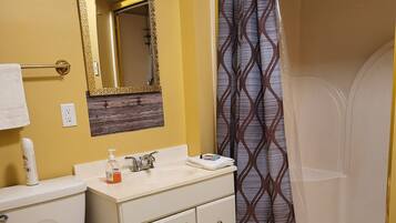 A bathroom with a toilet, sink, mirror, and shower curtain.