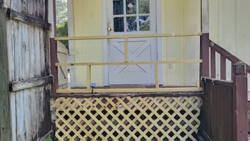 A wooden porch with a yellow door and a lattice railing.