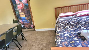 A room with a wooden bed, a desk with a chair, and a door with a floral curtain.