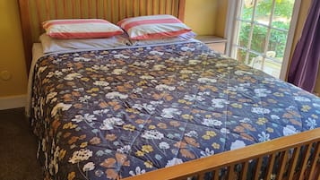 A bed with a floral bedspread, wooden headboard, and two pillows.