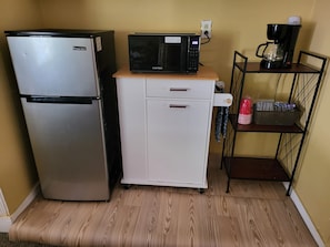 A compact kitchenette with a refrigerator, microwave, and coffee maker.