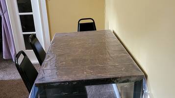 A room with a large table, two chairs, a door, and a light switch on the wall.