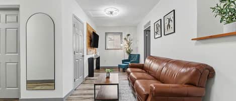 A modern living room with a leather sofa, a coffee table, and a rug.