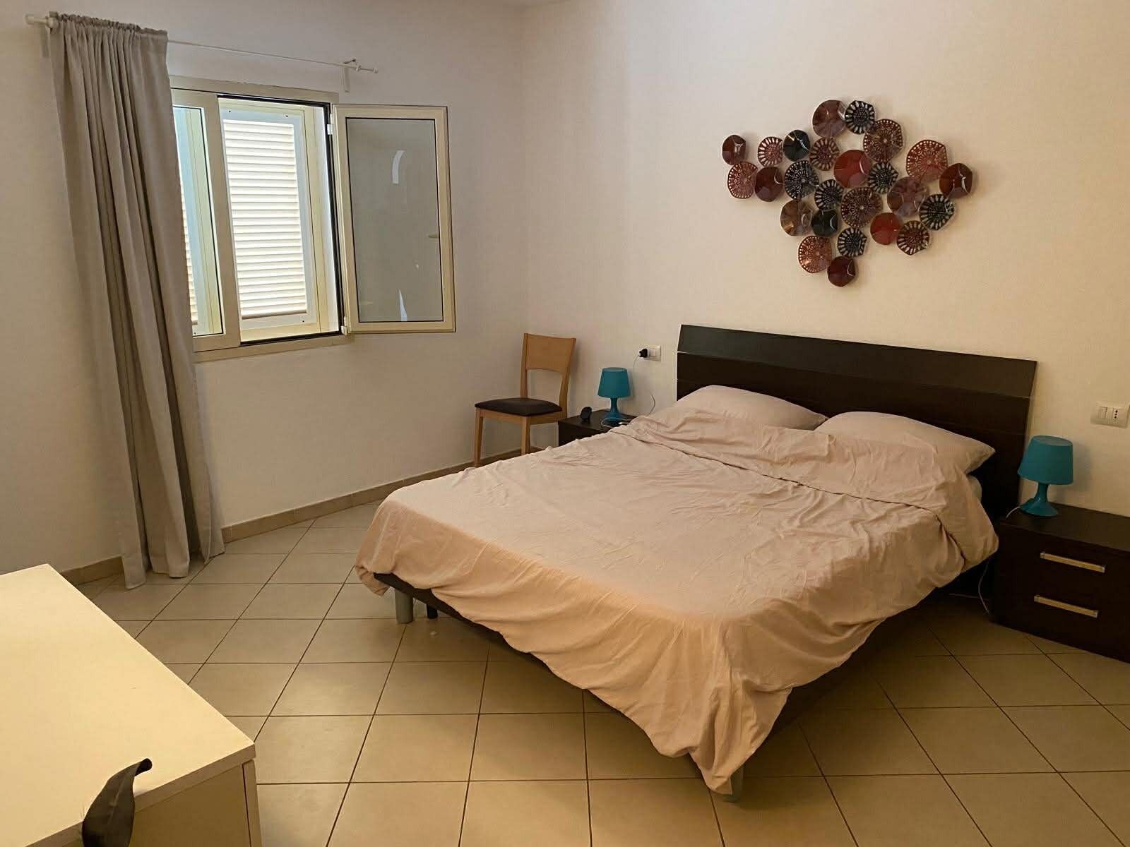 Un dormitorio con cama, una silla, un escritorio y un adorno en la pared.