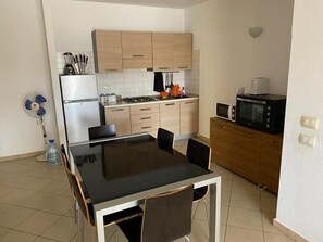 Eine kleine Küche mit Esstisch, Stühlen, einer Mikrowelle und einem Kühlschrank.