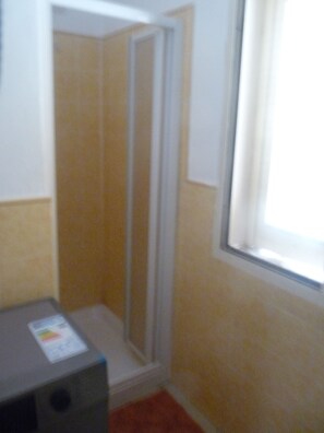 A bathroom with a shower, a toilet, and a window. - Peaceful 2-bedroom apartment with AC in Santa Maria. 400m from the beach. (Santa Maria)