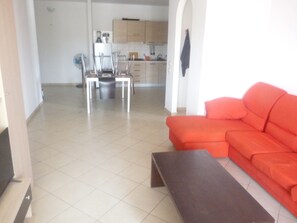 Ein Wohnzimmer mit einem roten Sofa, einem Couchtisch und einem Essbereich mit Stühlen und einem Tisch.